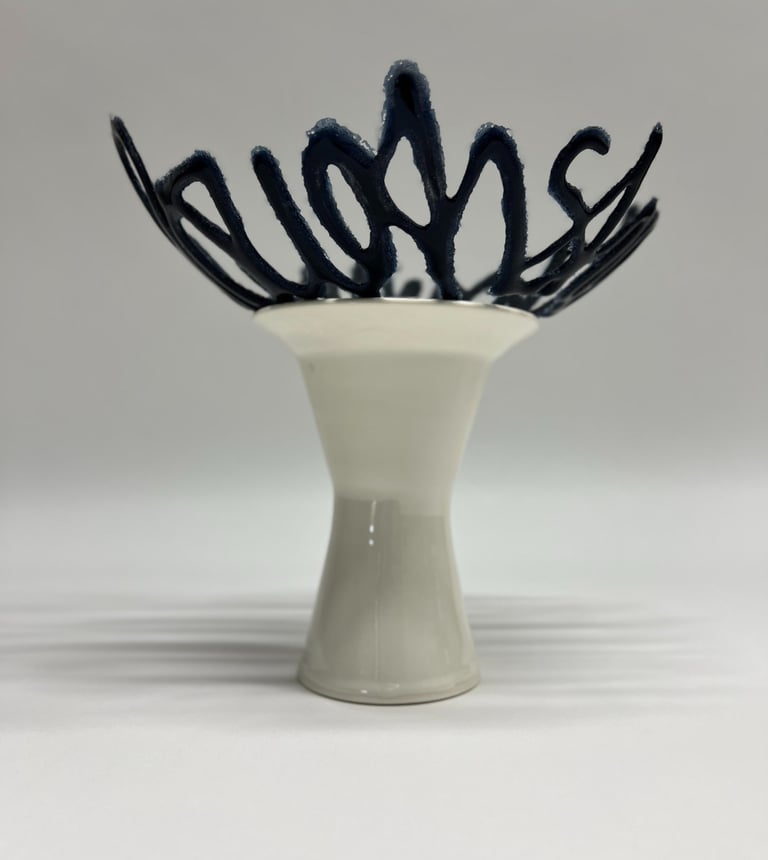 A blue glass bowl sculpture in the shape of a line of text, sitting on a porcelain ceramic pedestal