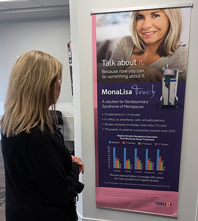 woman standing in doctors waiting room in front of a manalisa touch banner