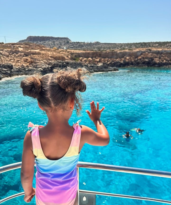 Child waving at mermaids swimming in the sea during a boat tour Cyprus