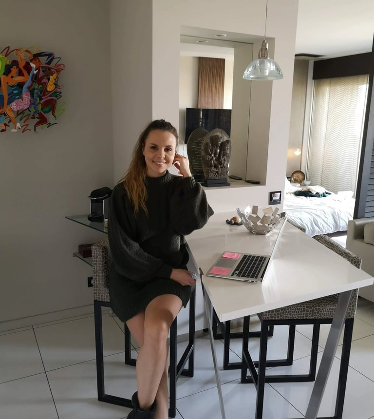 Christine Hauser, RTT Practitioner, sitting at a table with a laptop in a stylish home setting