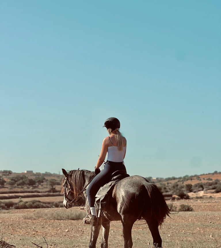 femme montant un cheval dans la campagne, avec un beau ciel bleu