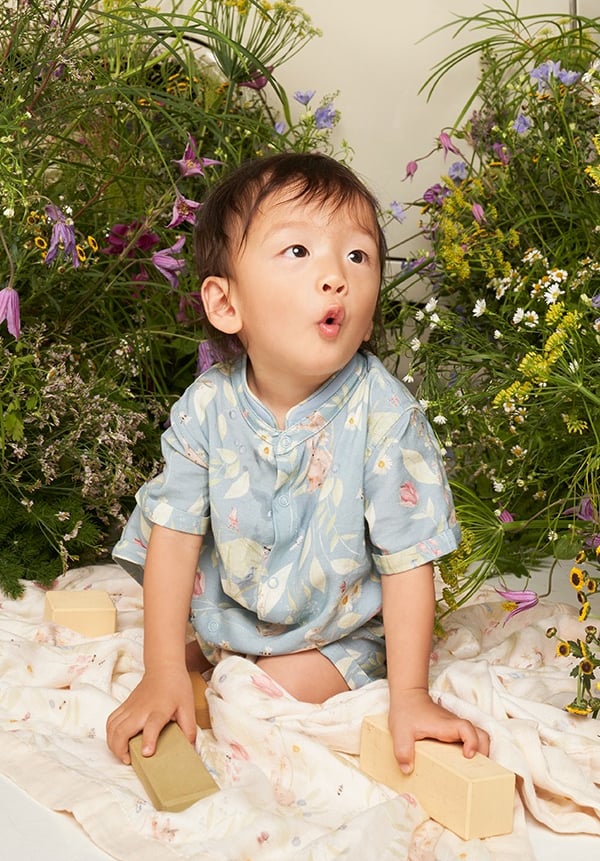 Bebê asiático veste macacão com estampa de arte original criada a mão da vida de um jardim
