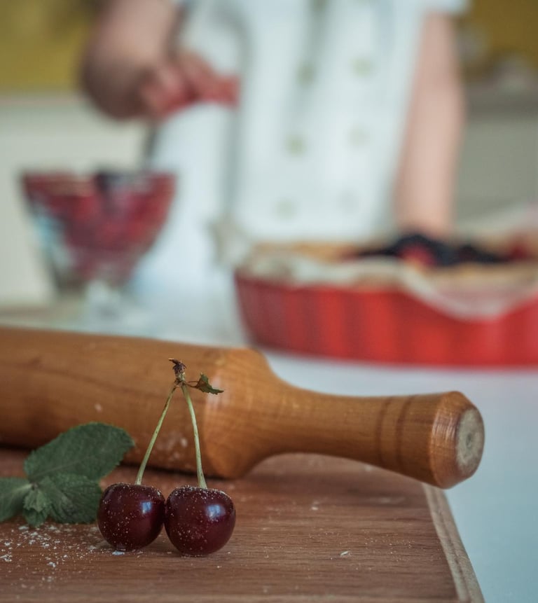 Fresh cherries and a wooden rolling pin on a table for homemade baking.