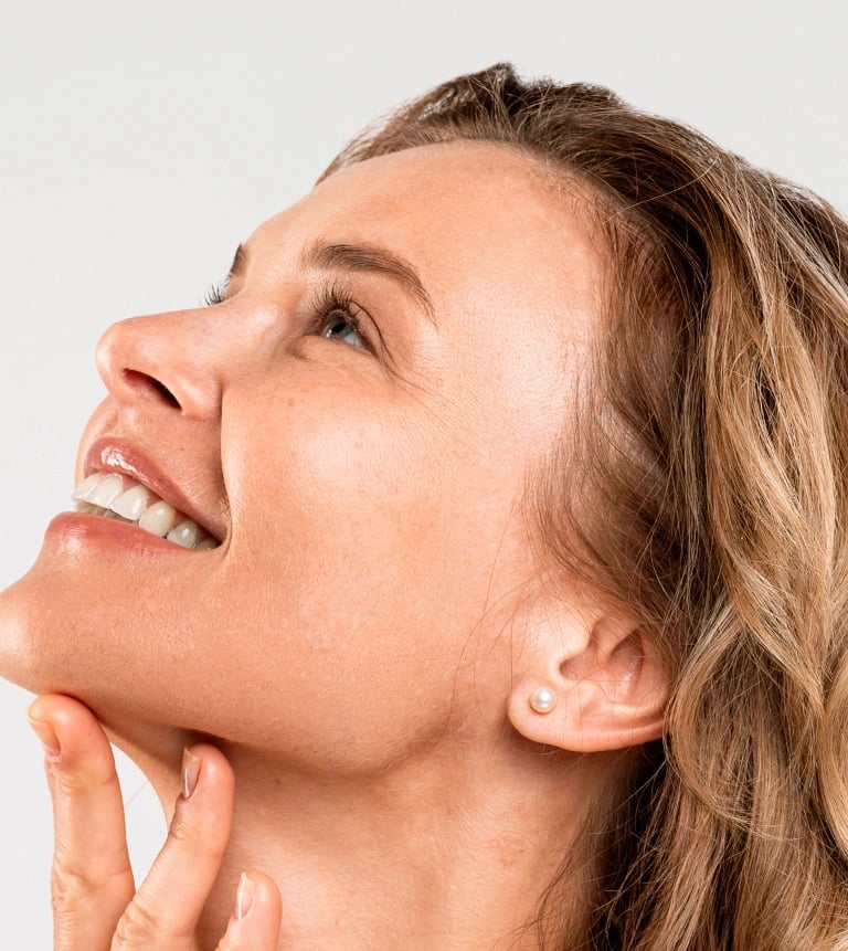 Woman looking up, touching her chin, showcasing a refined jawline.