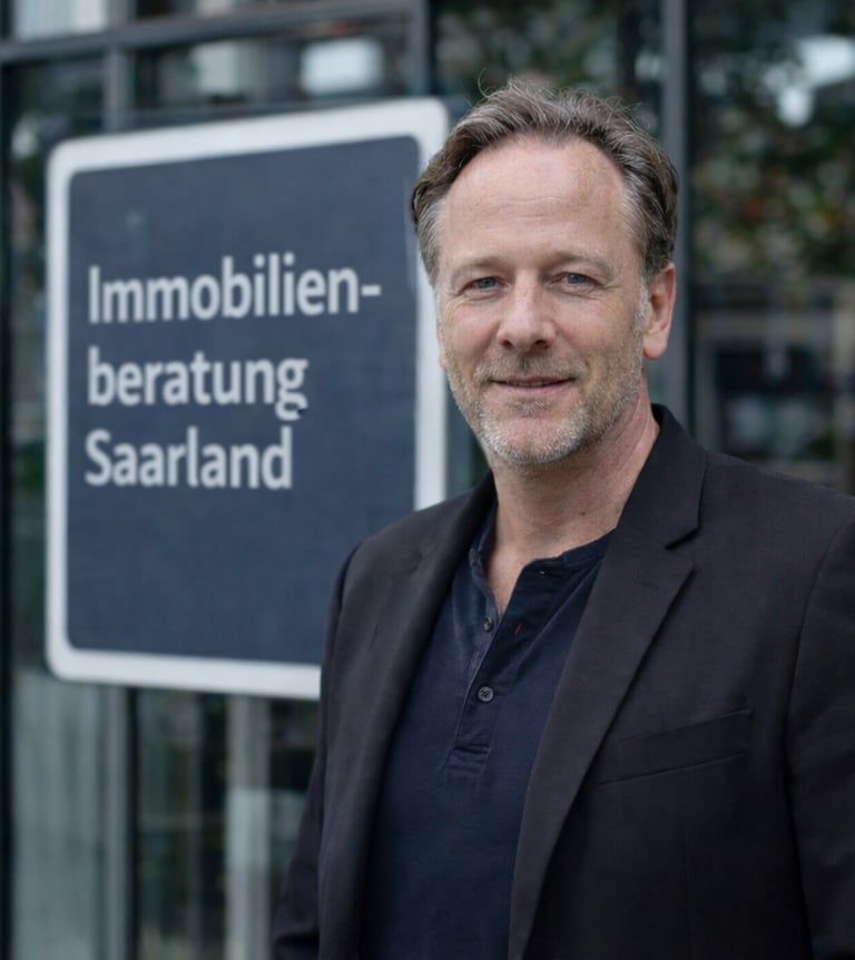 Professional real estate consultant in front of Immobilienberatung Saarland sign.