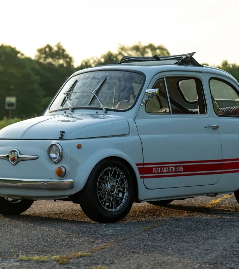 A photo of a blue grey 1974 Fiat 595 SS Abarth in a wooded setting at dusk.