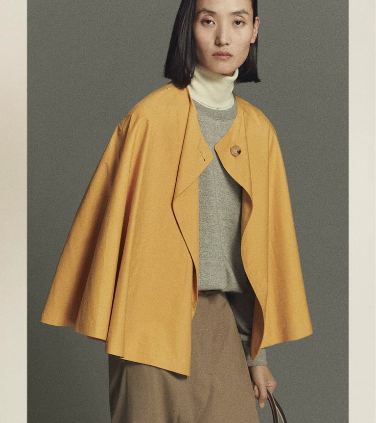 Woman wearing yellow cape jacket minimalist fashion.