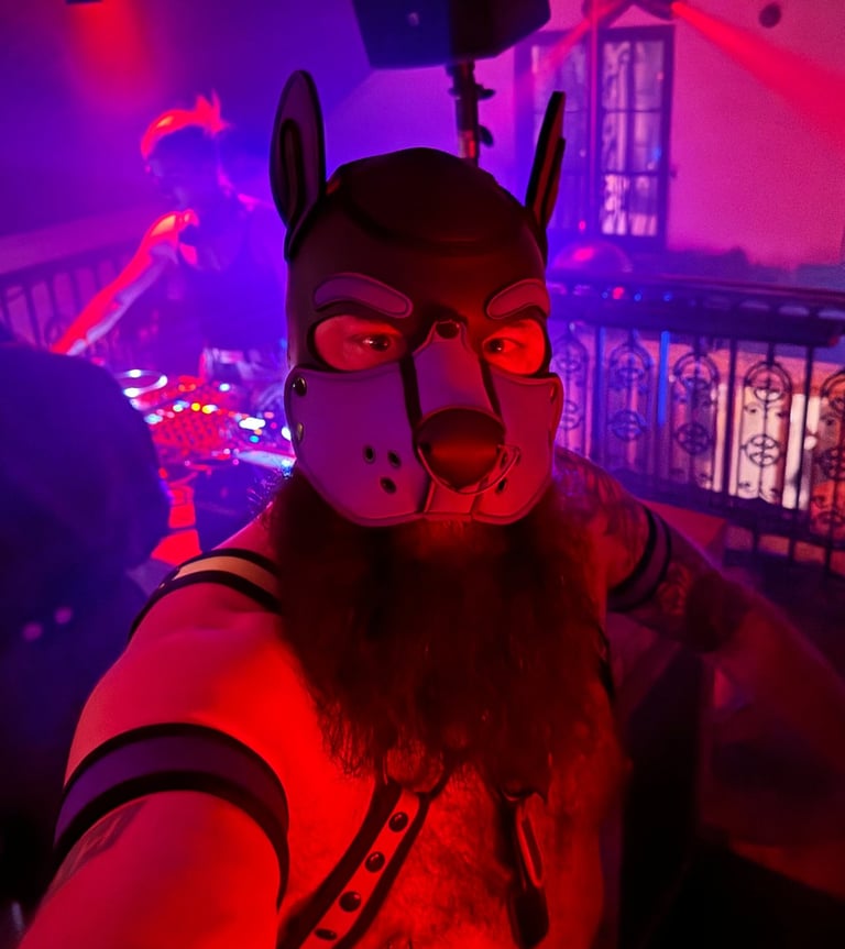 Man in a pup mask and bare chest taking a selfie in a club.