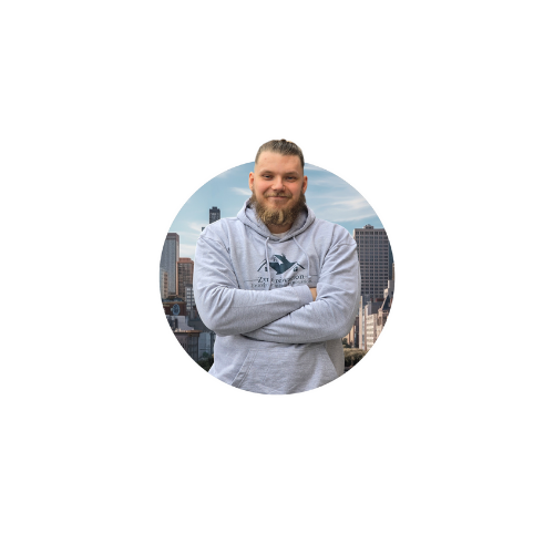 Zynel Bartosz, directeur de Zynel Rénovation, posant bras croisés devant un fond urbain, représentan