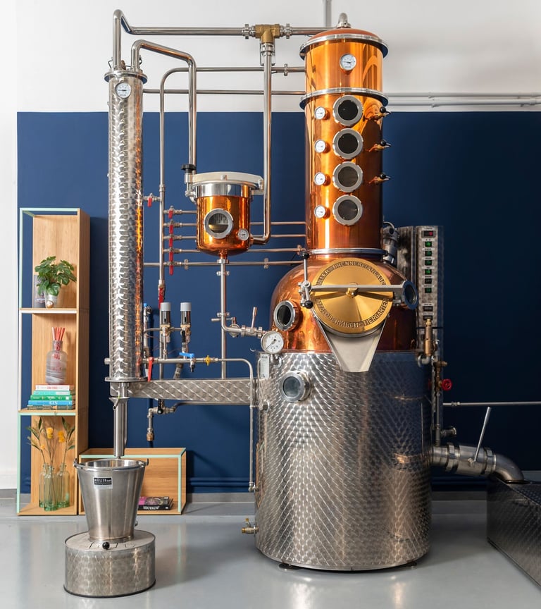 un bellissimo alambicco in rame, acciaio e ottone con un mobile, piante e libri su una parete blu