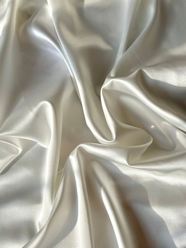 Elegant ivory white silk fabric with soft ripples and a luxurious satin sheen.