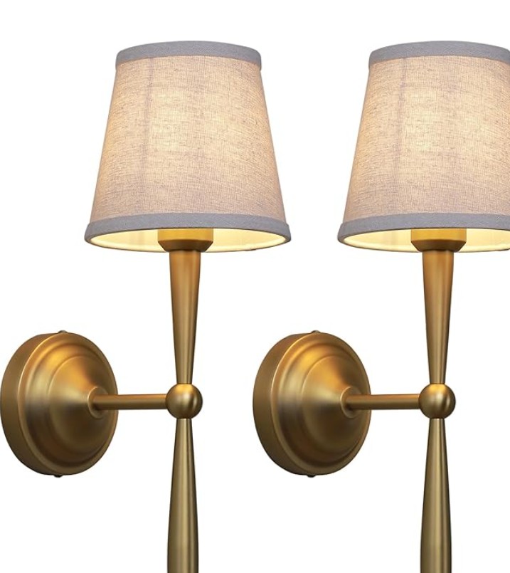 Pair of antique brass gold wall sconce lamps with light beige fabric shades.