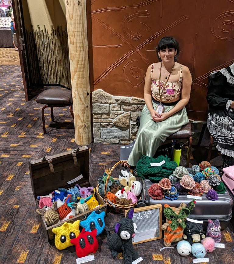 The constellation crochet founder sitting at a booth she set up at an event.