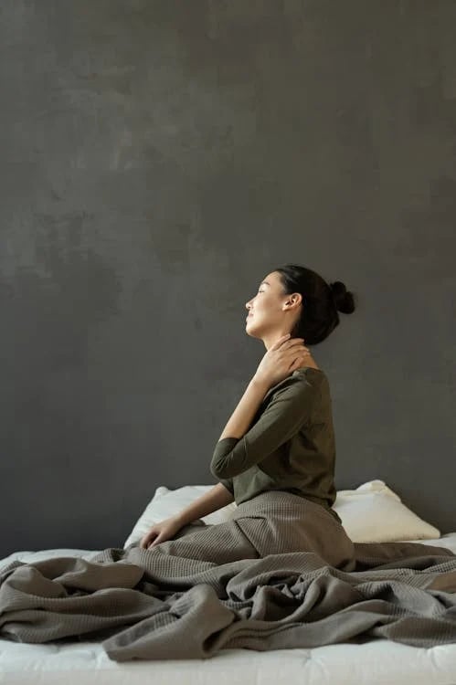 a woman sitting on a bed with a blanket on it