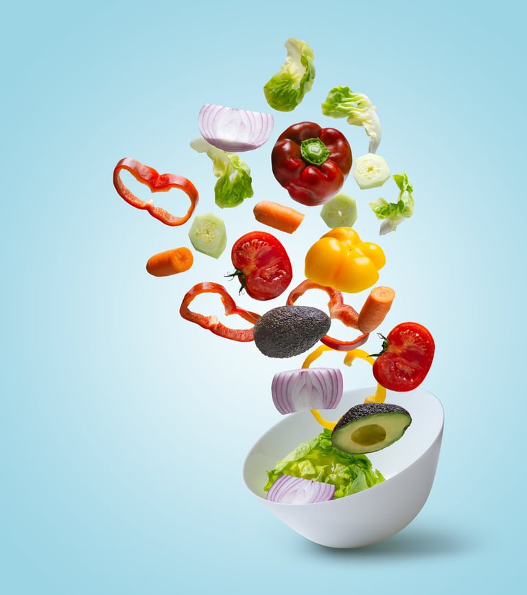 a bowl of vegetables being tossed in a bowl