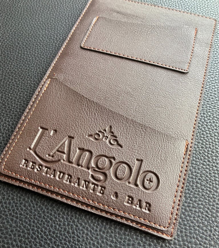 Fotoproducto de un portacuentas de similcuero, que tiene un logotipo grabado que dice "l'angolo"