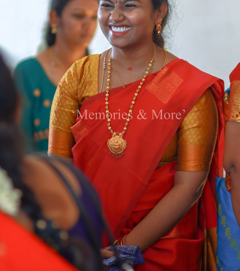 A woman in a red silk saree smiling at a wedding candid photograph by Memories and More Photography