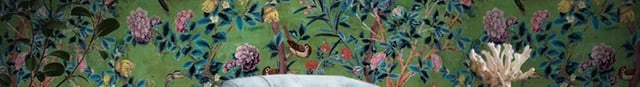Vintage style floral chinoiserie wallpaper in a home office with a blue armchair and wooden desk.