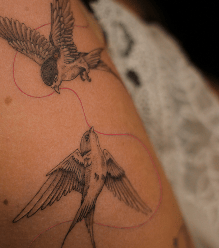 Tatouage d'oiseau avec un fil rouge sur le bras réalisé par Eva Ink Vlr