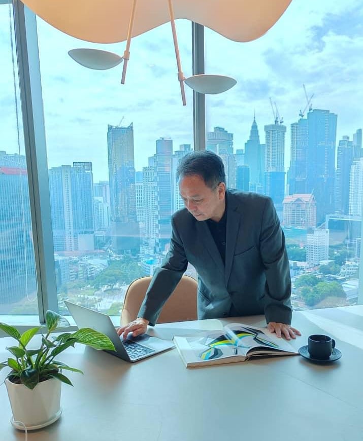 Professional businessman in a suit working on a laptop in a high-rise office with a city skyline view.