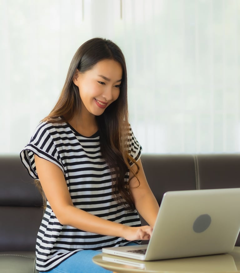 a woman sitting on a couch searching for job opening on her laptop
