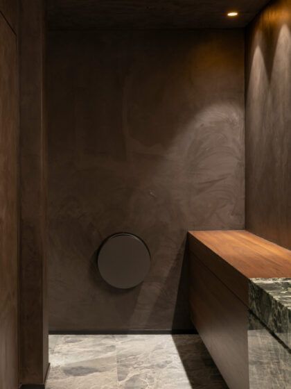 Modern luxury bathroom with dark textured walls, marble flooring, and a floating wood vanity.