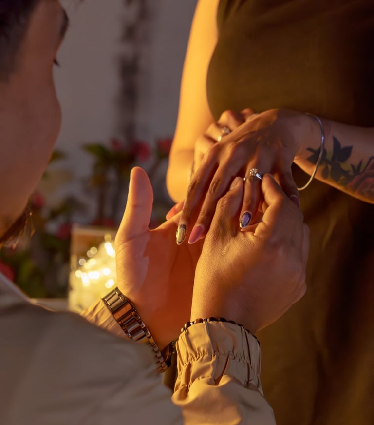 A man proposing by placing a diamond engagement ring on a woman's finger in a romantic setting.