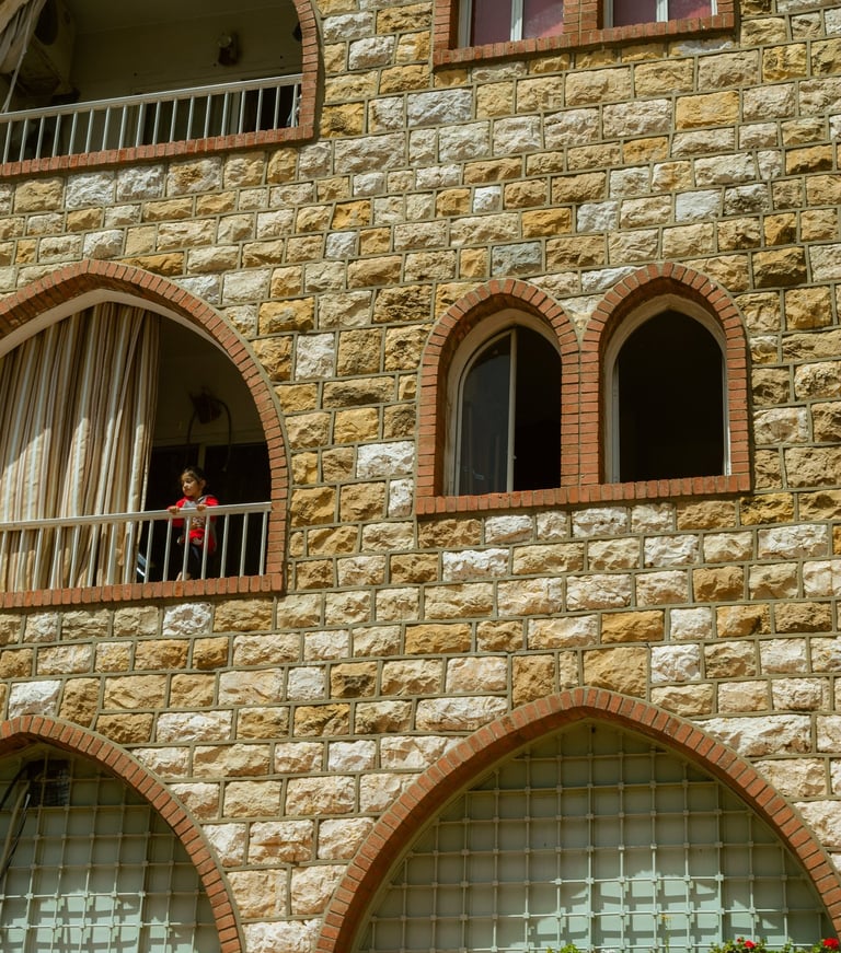 Photography Child standing on a balcony of building with arched windows in Brummana, Lebanon