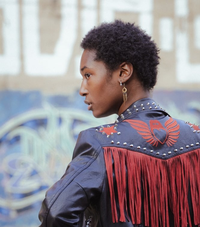 An over the shoulder shot of a model with cool earrings and a black leather jacket.