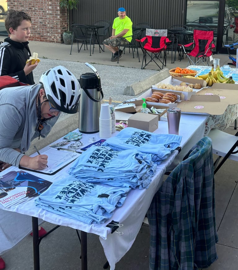 Mayor Barbara Buffaloe, wearing a bike helmet, filling out her name, at a table with pastries