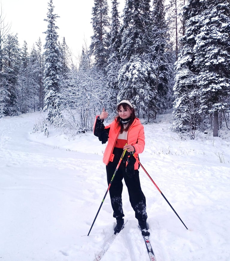 a woman in a pink jacket and black pants is standing in the snow with cross-country skis