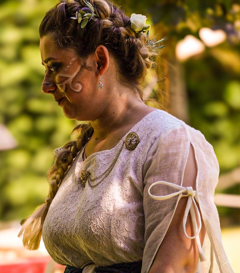 Retrato de la novia con vestido medieval y trenza adornada con flores, mirando hacia abajo