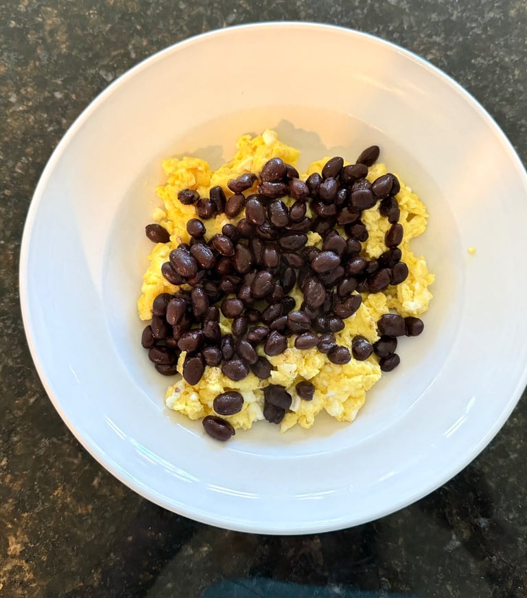 Scrambled eggs topped with black beans in a simple breakfast bowl.