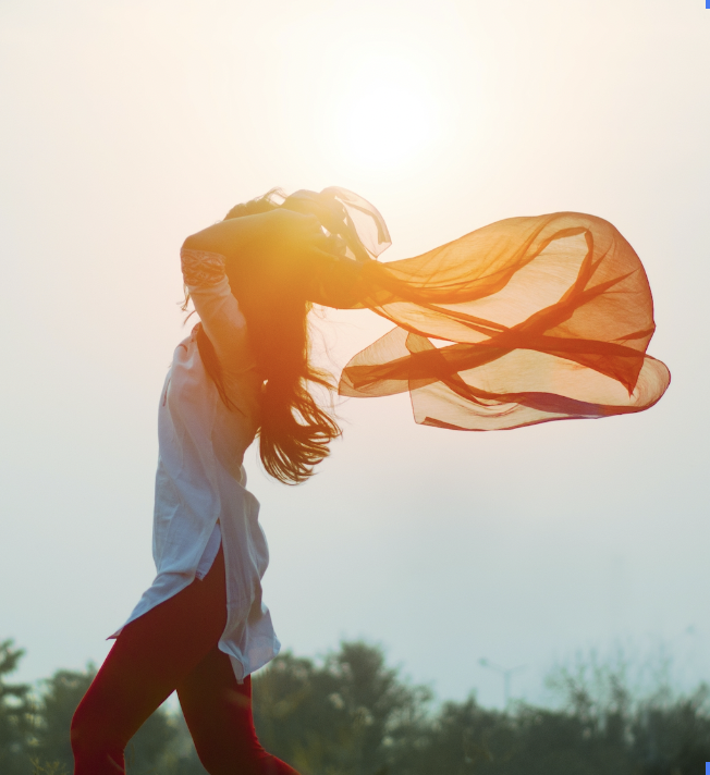woman with flowing orange scarf in wind and sunlight