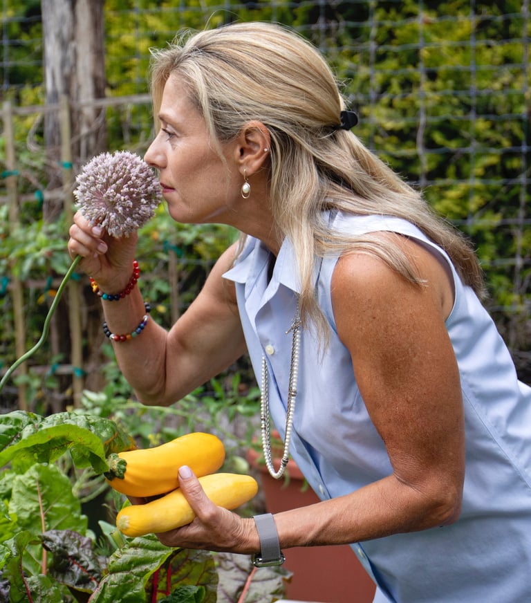 a woman in a blue shirt is holding a Garlic Chive Blossom