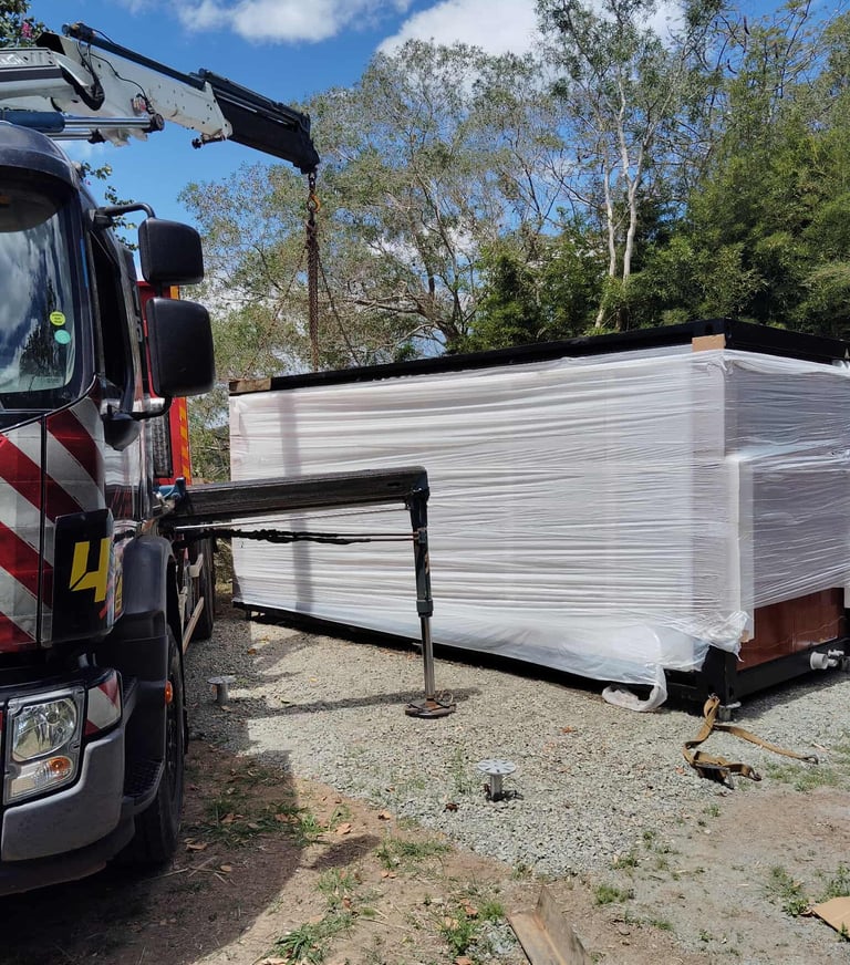 Livraison d'une maison modulaire préfabriquée par camion avec grue.