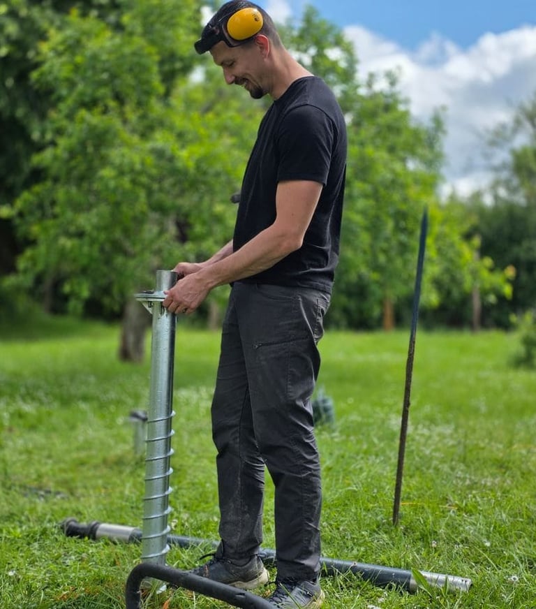 Ouvrier qui pose une vis de fondation pour un abri de jardin