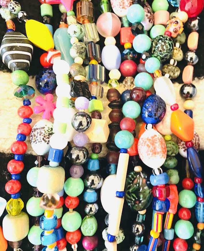 A colorful collection of handmade necklaces featuring vibrant glass beads, stars, and diverse textures.