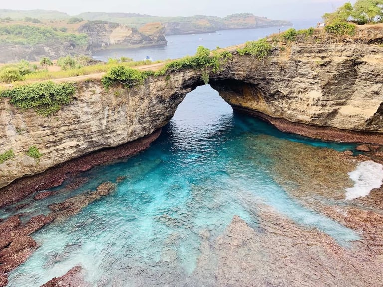 Broken Beach in Nusa Penida, Bali, featuring a natural rock arch over turquoise ocean water.