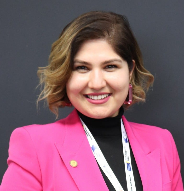 Professional woman in pink coat and black blouse smiling