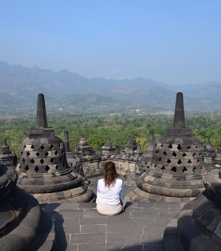 a woman sitting on a stone wall in a temple