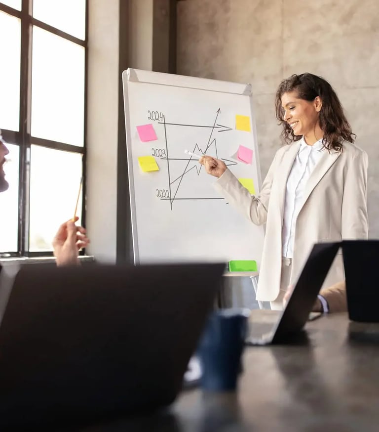 A happy business woman in a meeting room showing business growth on a small whiteboard
