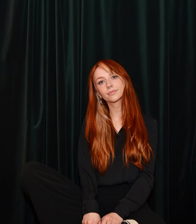 a woman sitting on a stool with a black top, marleenska
