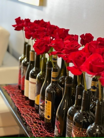 a row of wine bottles with red roses in them