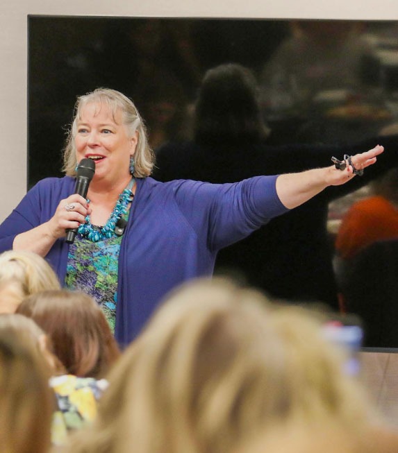 Debbie Chen speaking to an audience with a microphone, Business Leadership Coach and speaker.