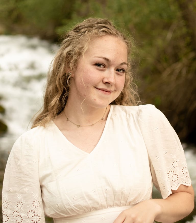 a woman in a white dress standing in front of a river