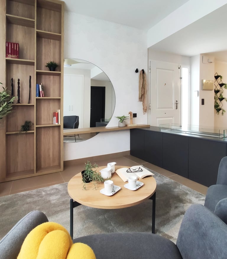 Decoración de interiores de zona relax con librería de madera, chimenea de bioetanol y butaca en San Antonio de Benaguér