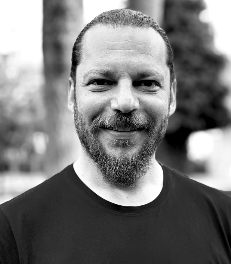 Alper Sümengen Tai Ji Qi Gong and sword instructor of WDP Turkey, smiling outdoors in black shirt