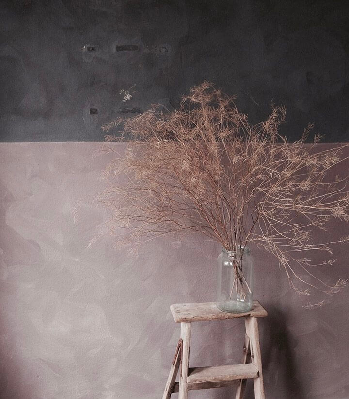 a vase with dried twigs in a vase on a wooden table
