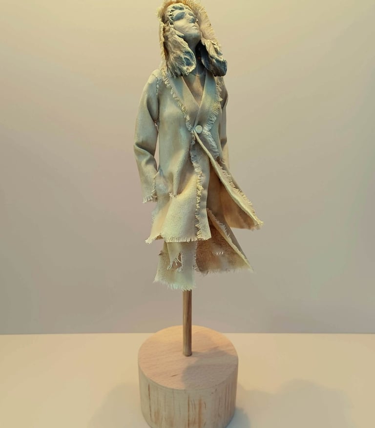 Clay and canvas sculpture of a female figure gazing upwards, wearing windswept, ragged clothes.